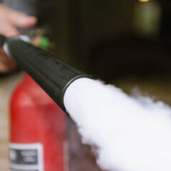 Close up taken as a man fires a carbon dioxide fire extinguisher.